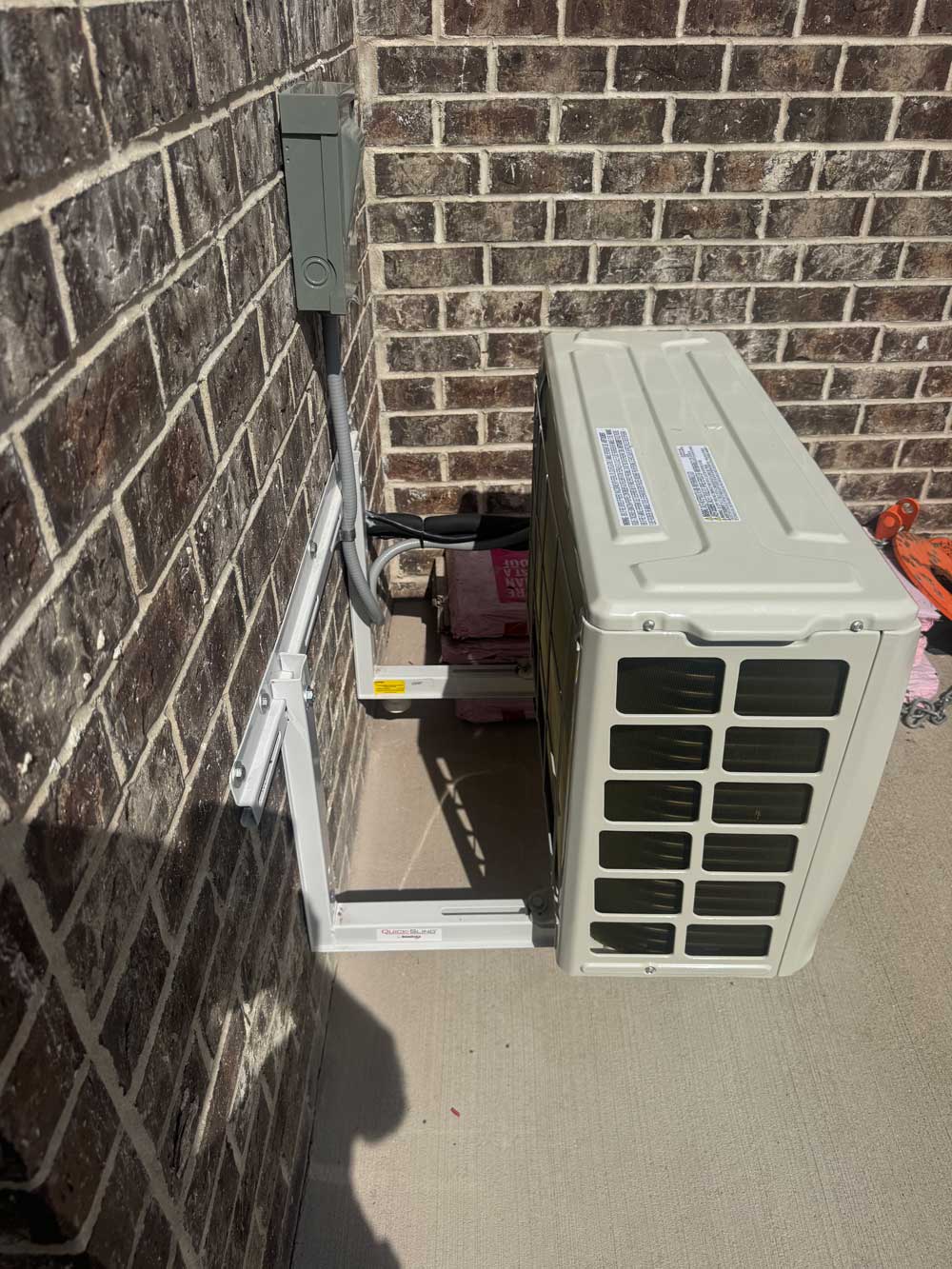Outdoor HVAC condenser installed beside a brick wall